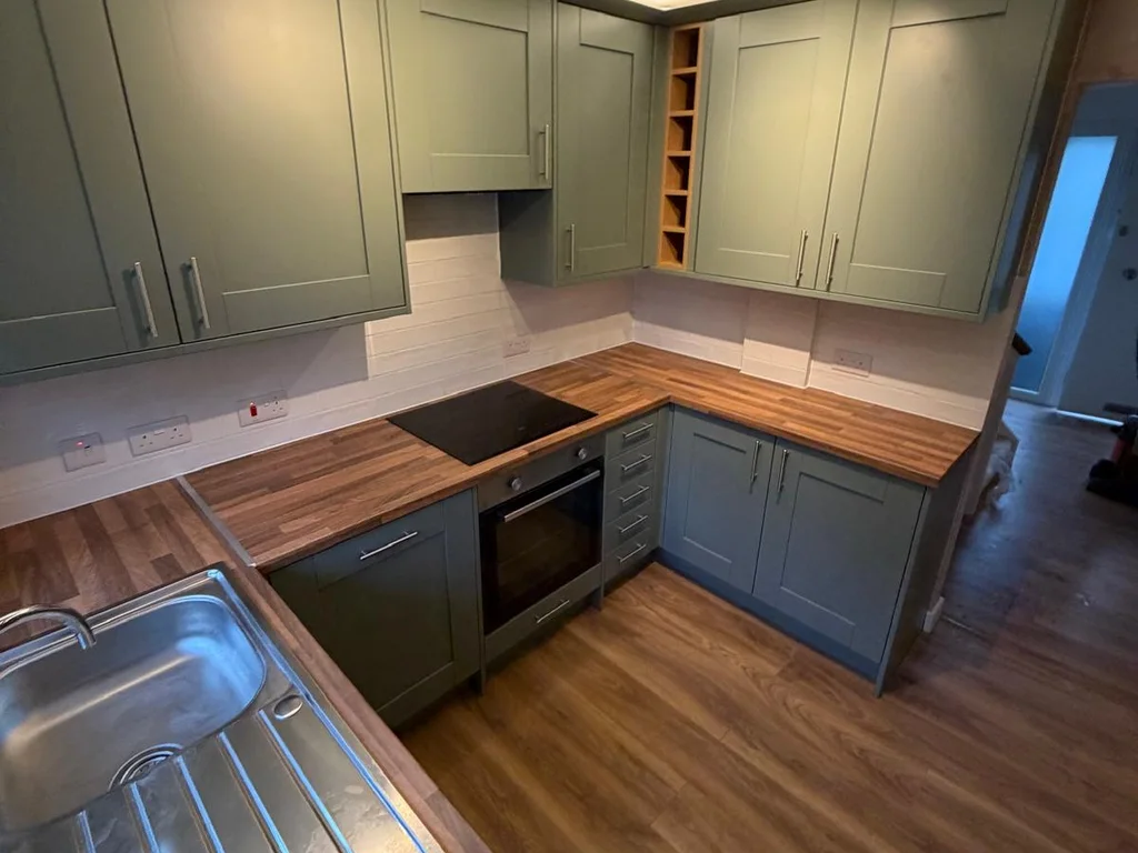 Green shaker kitchen with LED lighting above the wall cabinets and a ceiling spotlight bar